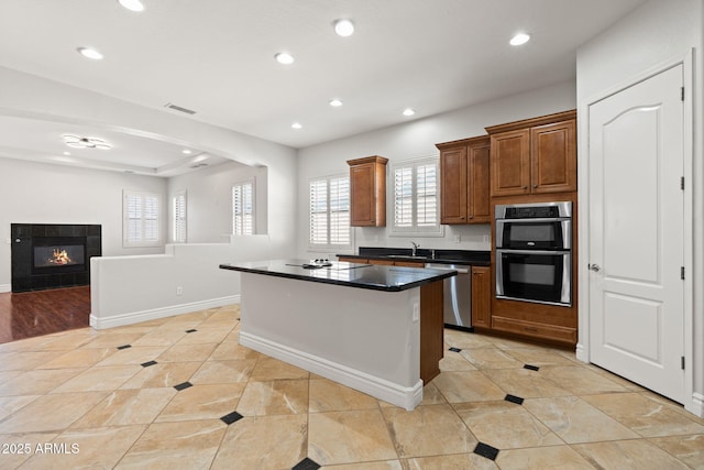 3215 E Constance Way, Phoenix, AZ 85042 - kitchen with appliances with stainless steel finishes, recessed lighting, dark countertops, a kitchen island, and plenty of natural light