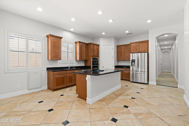 3215 E Constance Way, Phoenix, AZ 85042 - kitchen with stainless steel appliances, arched walkways, recessed lighting, dark countertops, and brown cabinetry