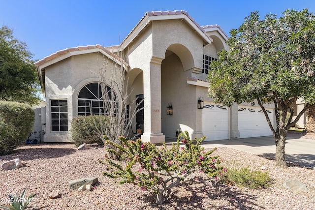 view of front facade with a garage, driveway, a tiled roof, and stucco siding