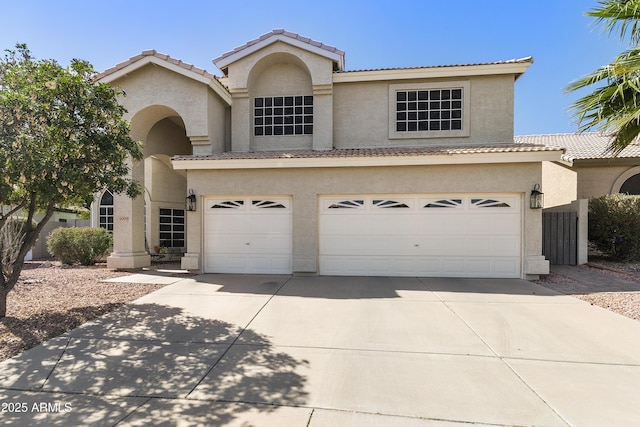 traditional-style home featuring a garage, a tile roof, concrete driveway, and stucco siding