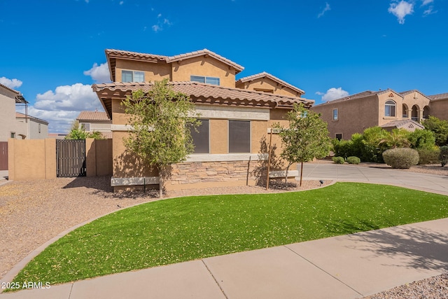 mediterranean / spanish-style home with a tile roof, a gate, fence, a front lawn, and stucco siding