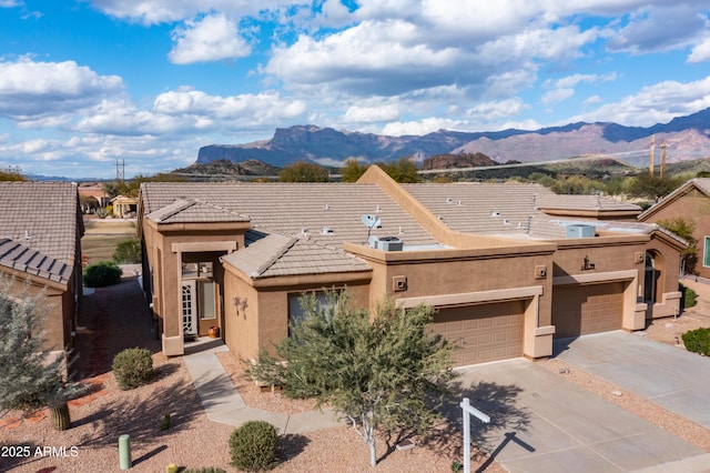 view of front of property with concrete driveway, a garage, a mountain view, and stucco siding