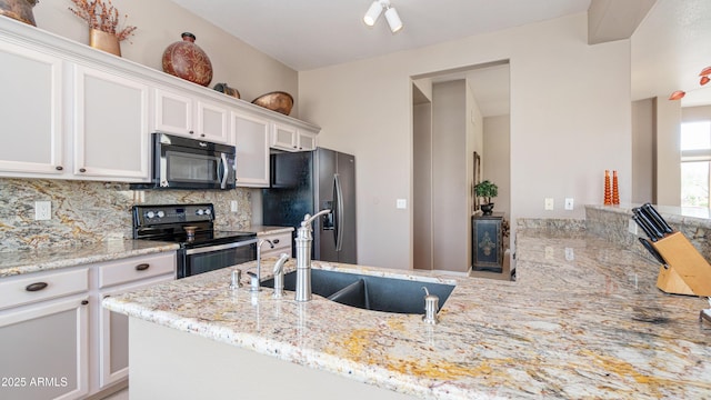 kitchen featuring a sink, light stone counters, white cabinetry, stainless steel appliances, and decorative backsplash