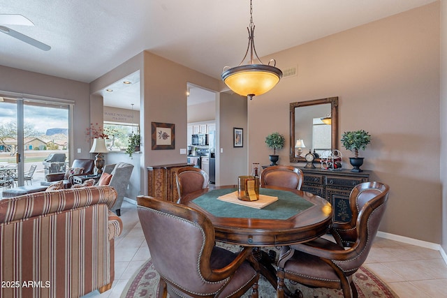 dining space with light tile patterned floors, visible vents, baseboards, and ceiling fan