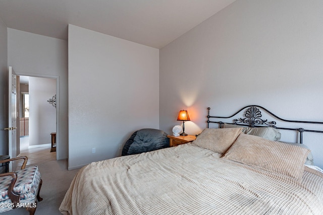 bedroom with light colored carpet, baseboards, and vaulted ceiling