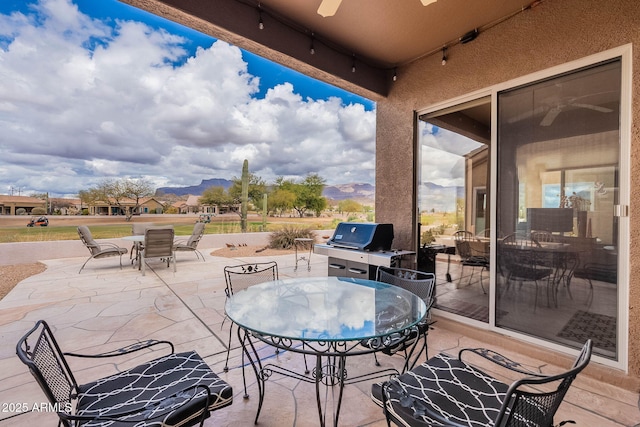 view of patio / terrace featuring outdoor dining space, a mountain view, and grilling area