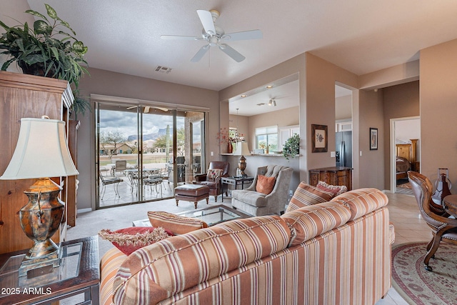 living area featuring light tile patterned floors, visible vents, and ceiling fan