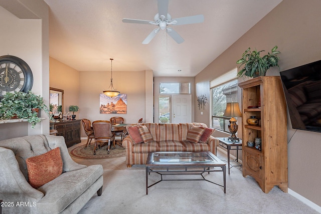 living room featuring light colored carpet, baseboards, and ceiling fan