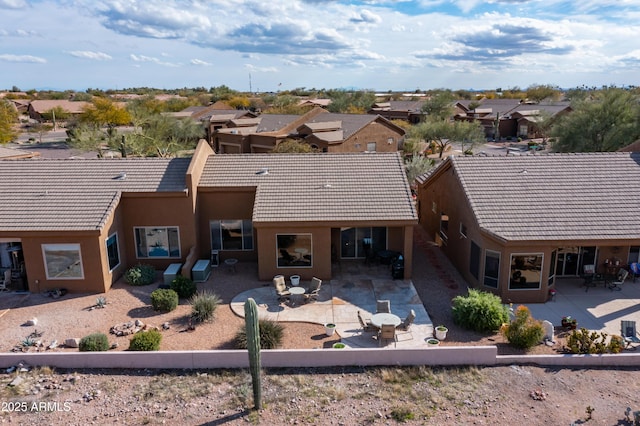 rear view of house featuring a patio area, stucco siding, and a tiled roof