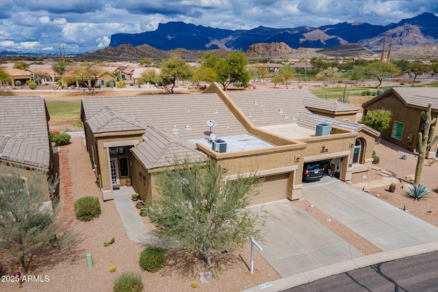 view of front facade with stucco siding, a mountain view, an attached garage, and driveway