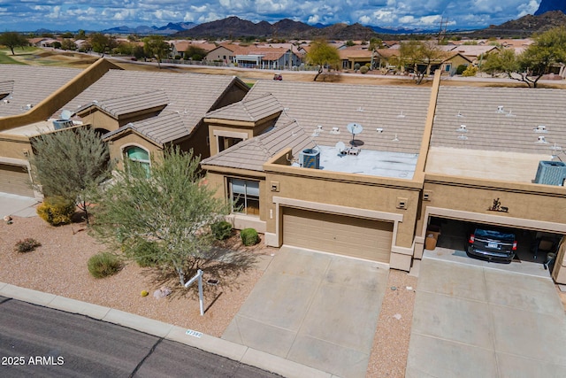 view of front of property featuring driveway, a mountain view, an attached garage, stucco siding, and a residential view