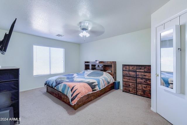 carpeted bedroom featuring a textured ceiling and ceiling fan