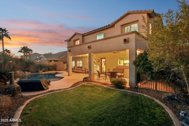 back of house featuring a patio, fence private yard, a lawn, a fenced in pool, and stucco siding