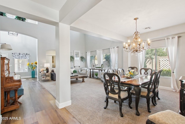 dining area with arched walkways, a healthy amount of sunlight, visible vents, and wood finished floors