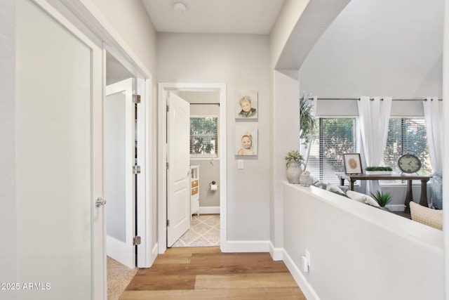 hallway with plenty of natural light, light wood-style flooring, and baseboards