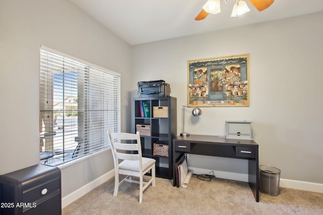 carpeted office space featuring ceiling fan and baseboards