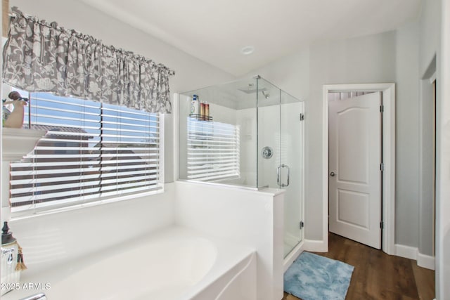 full bath featuring wood finished floors, a shower stall, and a bath