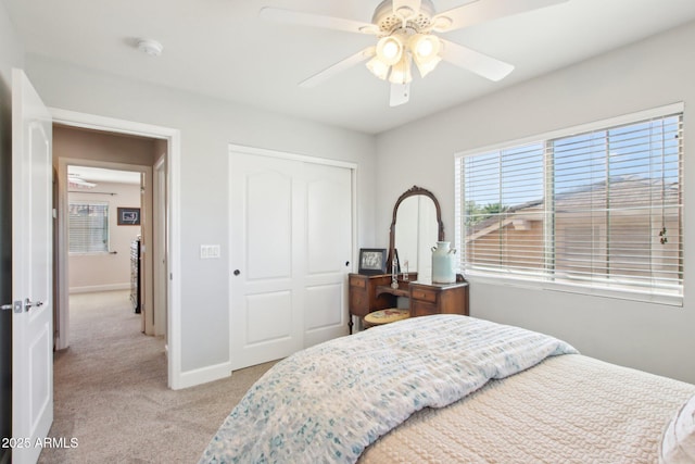 bedroom with light carpet, ceiling fan, baseboards, and a closet