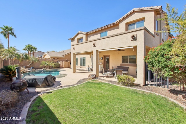 rear view of property featuring a lawn, a fenced in pool, a patio, fence, and stucco siding