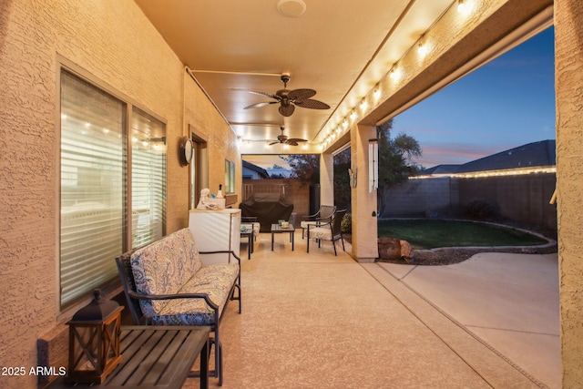 patio terrace at dusk featuring a fenced backyard and ceiling fan