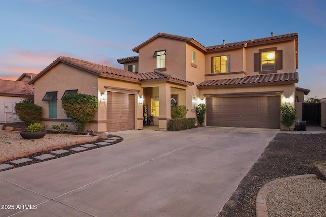 mediterranean / spanish-style house featuring driveway, an attached garage, a tiled roof, and stucco siding