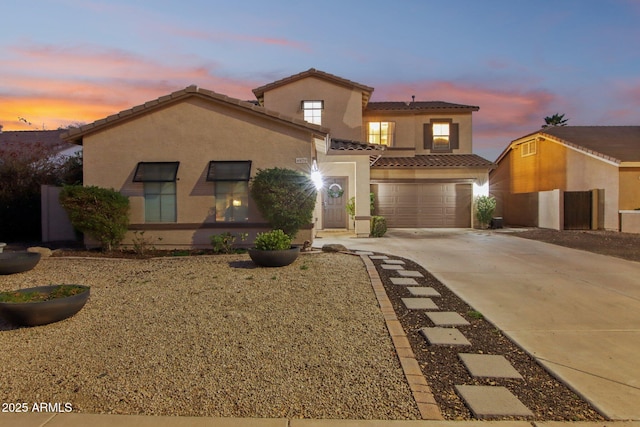 mediterranean / spanish-style home featuring concrete driveway, a tile roof, an attached garage, and stucco siding