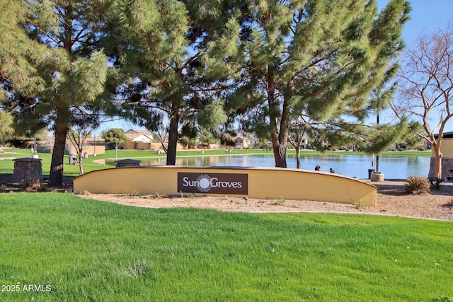 community sign featuring a lawn and a water view