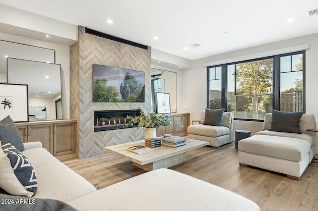 living room with a tile fireplace and light hardwood / wood-style flooring