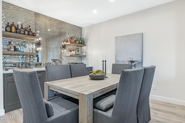 dining space with indoor bar and light hardwood / wood-style floors