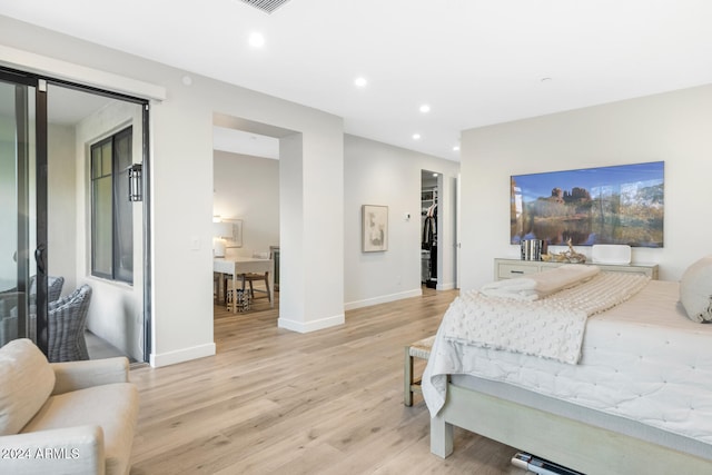 bedroom featuring a spacious closet, a closet, and light hardwood / wood-style floors