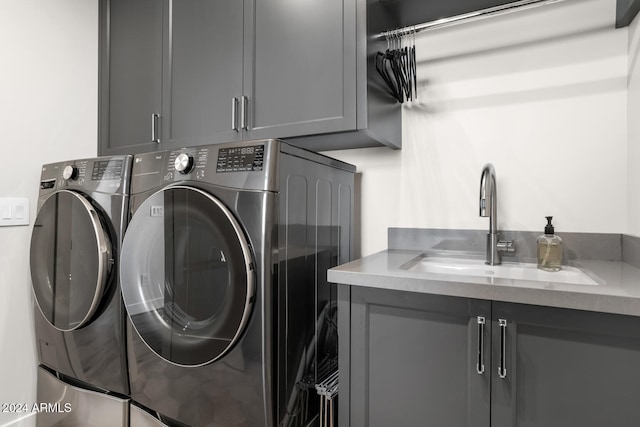 laundry area featuring washer and clothes dryer, cabinets, and sink