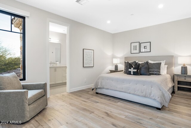 bedroom with connected bathroom and light wood-type flooring