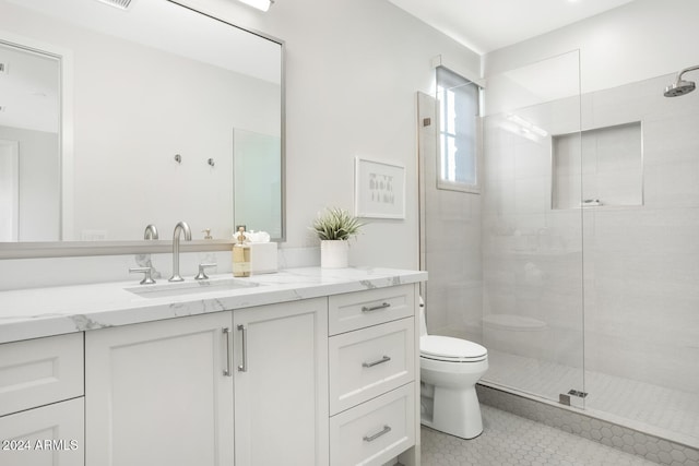 bathroom with tile patterned floors, vanity, toilet, and tiled shower