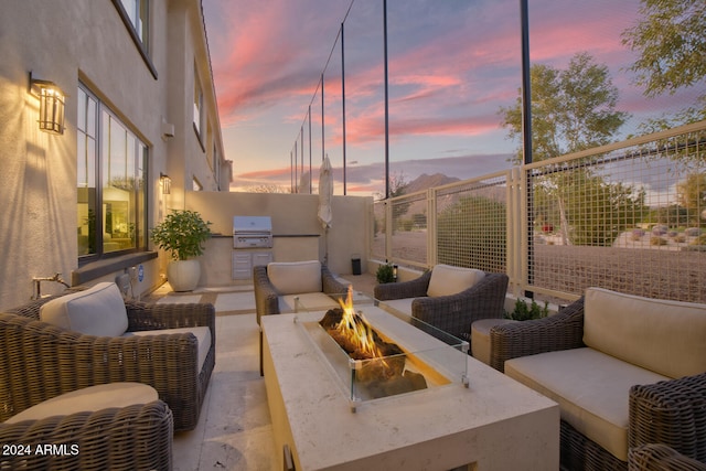 patio terrace at dusk with exterior kitchen and an outdoor living space with a fire pit