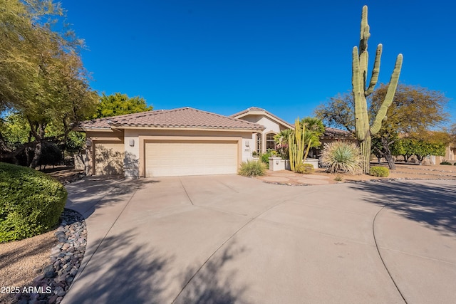 mediterranean / spanish home featuring a garage, concrete driveway, a tiled roof, and stucco siding