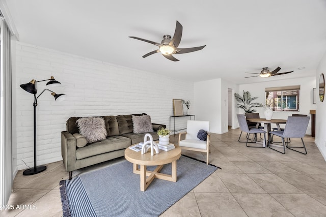 living area with brick wall, a ceiling fan, and light tile patterned floors