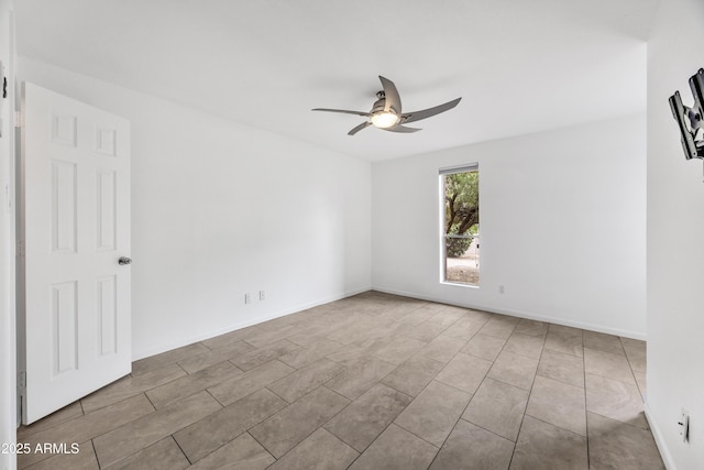 tiled empty room featuring a ceiling fan