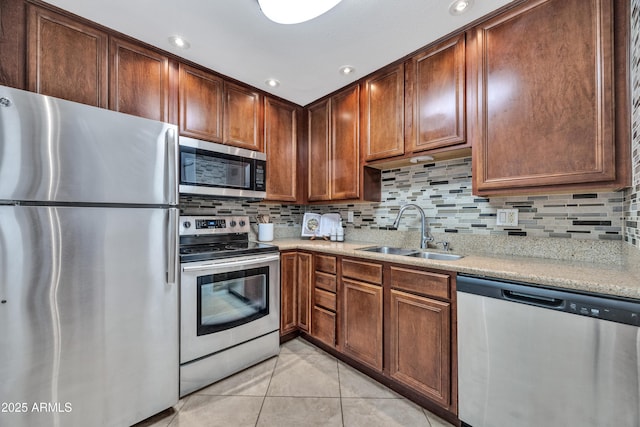 kitchen with appliances with stainless steel finishes, a sink, light tile patterned flooring, tasteful backsplash, and recessed lighting