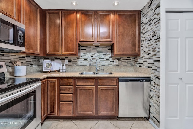 kitchen with stainless steel appliances, a sink, light tile patterned floors, and light countertops