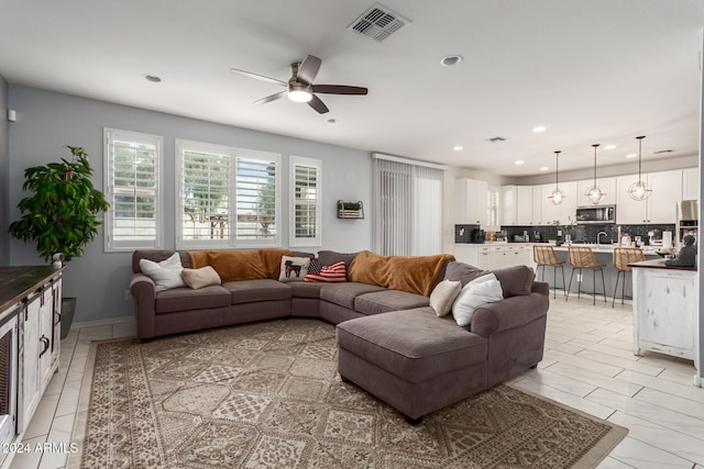 tiled living room featuring ceiling fan and sink