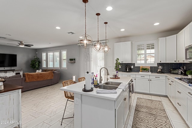 kitchen featuring backsplash, a center island with sink, a wealth of natural light, and sink