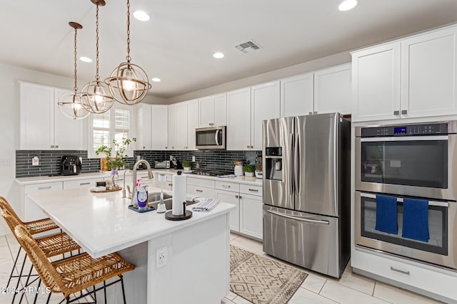 kitchen featuring white cabinetry, stainless steel appliances, an inviting chandelier, decorative light fixtures, and a kitchen island with sink