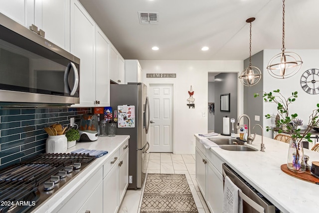 kitchen featuring decorative backsplash, stainless steel appliances, sink, pendant lighting, and white cabinets