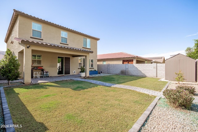 back of house with a patio area, a storage shed, and a yard