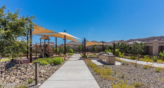 surrounding community featuring an outdoor kitchen, a mountain view, and a playground