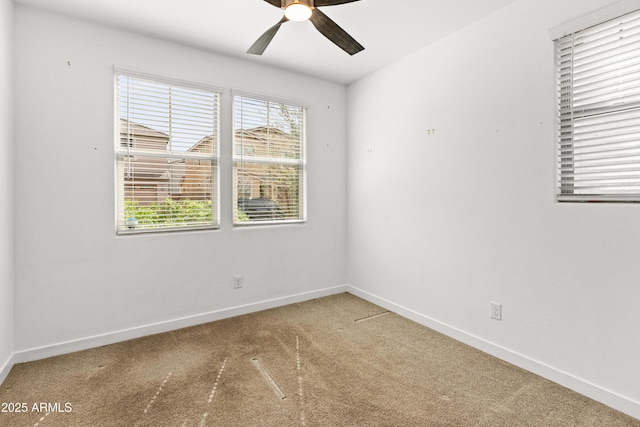 carpeted spare room featuring a ceiling fan and baseboards