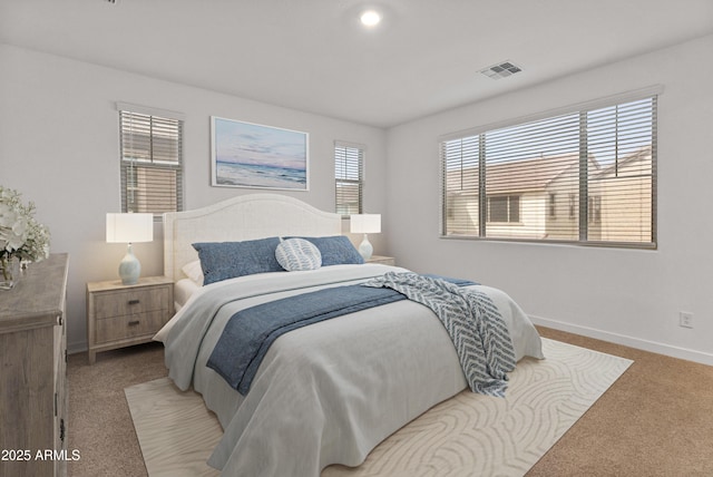 bedroom featuring light colored carpet, visible vents, baseboards, and multiple windows