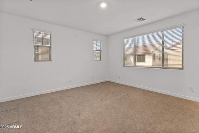 empty room with light carpet, visible vents, and baseboards