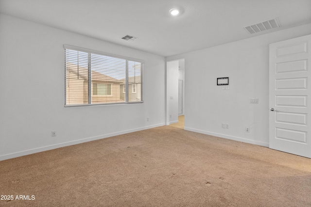 empty room with baseboards, visible vents, and light colored carpet