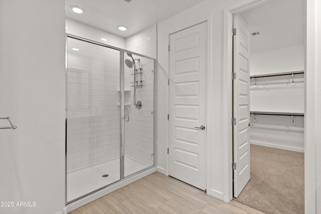 bathroom featuring a walk in closet, a shower stall, and recessed lighting